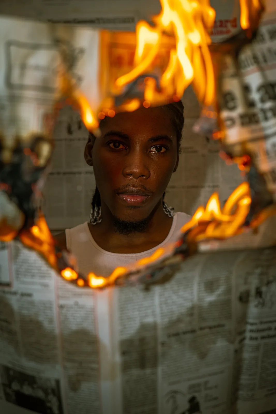 RGR SHOOT, Portrait studio, le visage vu à travers un journal en flammes, regard à l'objectif
